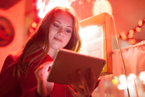 Girl on tablet in red light bar