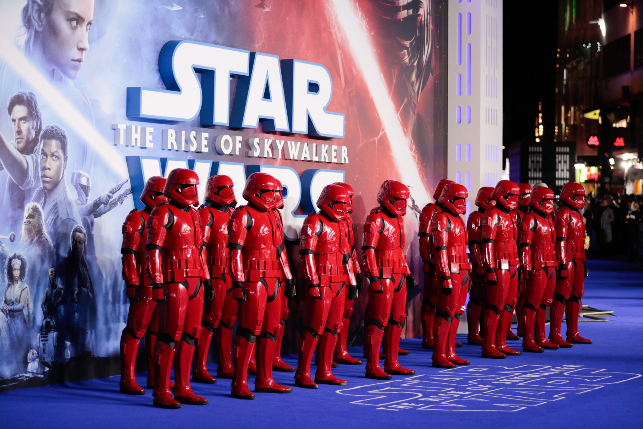 Stormtroopers in red uniforms lined up against Star Wars: The Rise of Skywalker poster