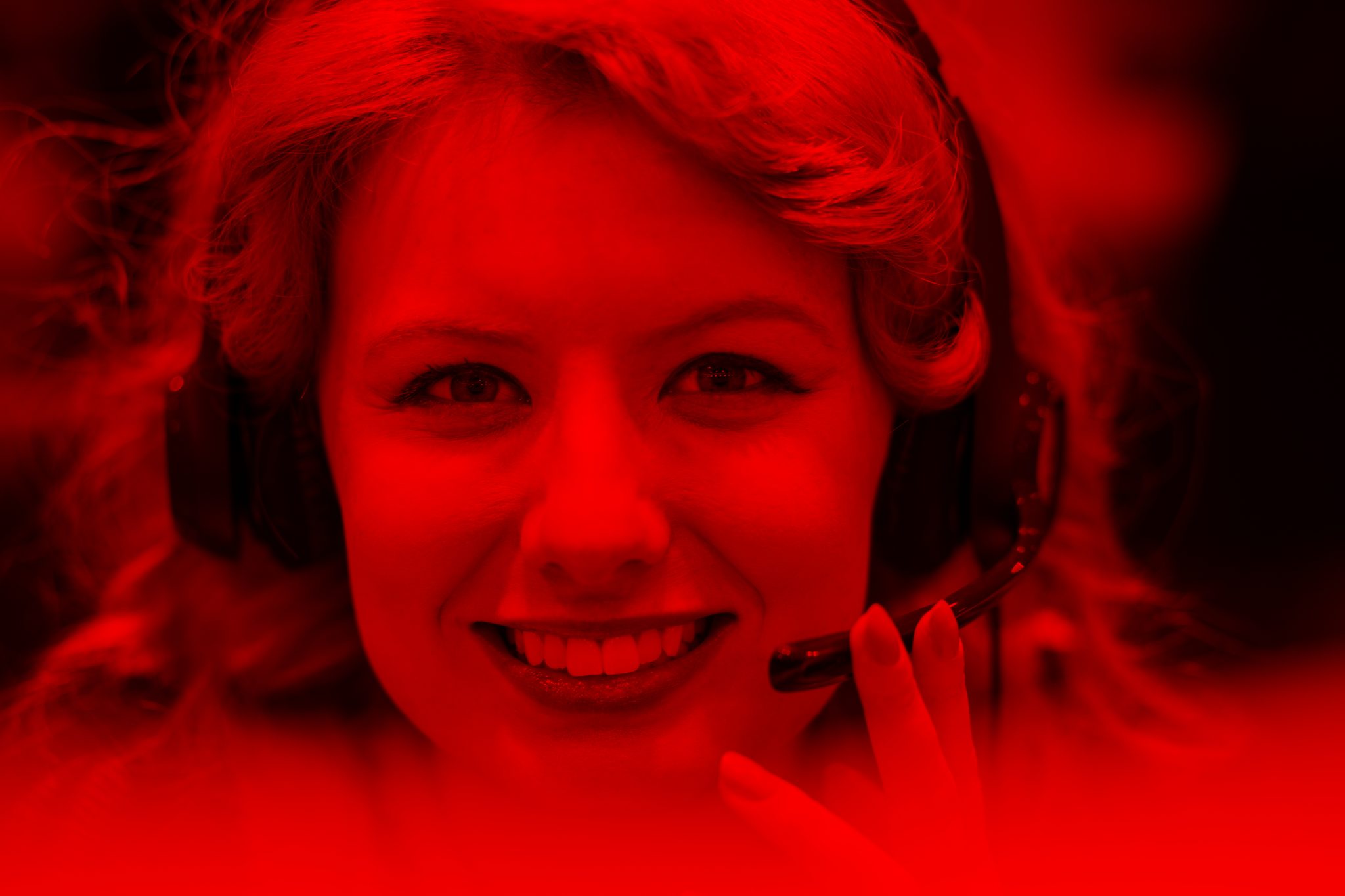 Smiling woman on call centre headset with red filter