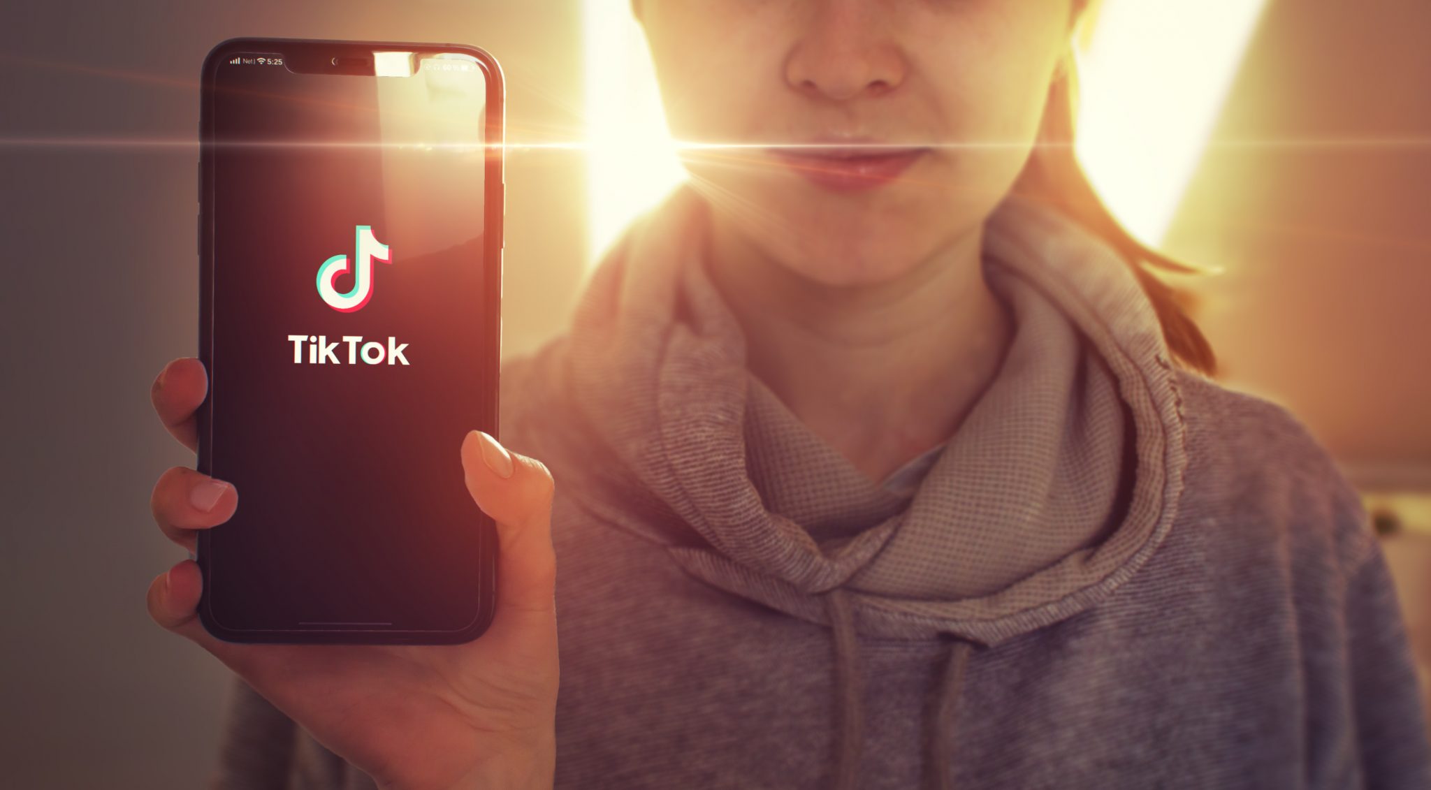 Young girl holding phone showing TikTok app