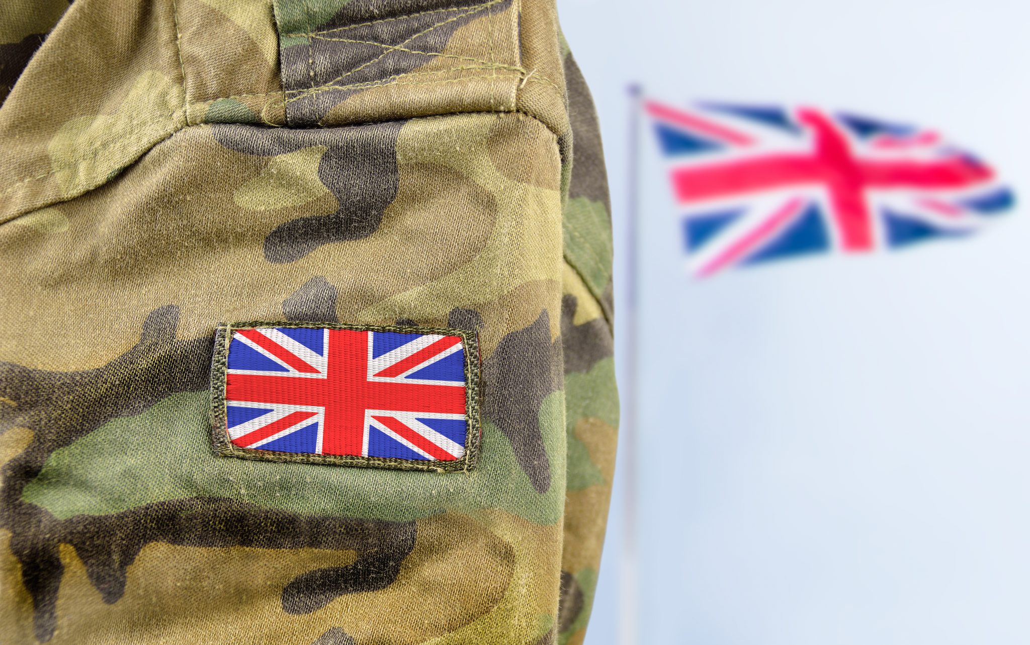 Miltary person standing in front of Union Jack flag