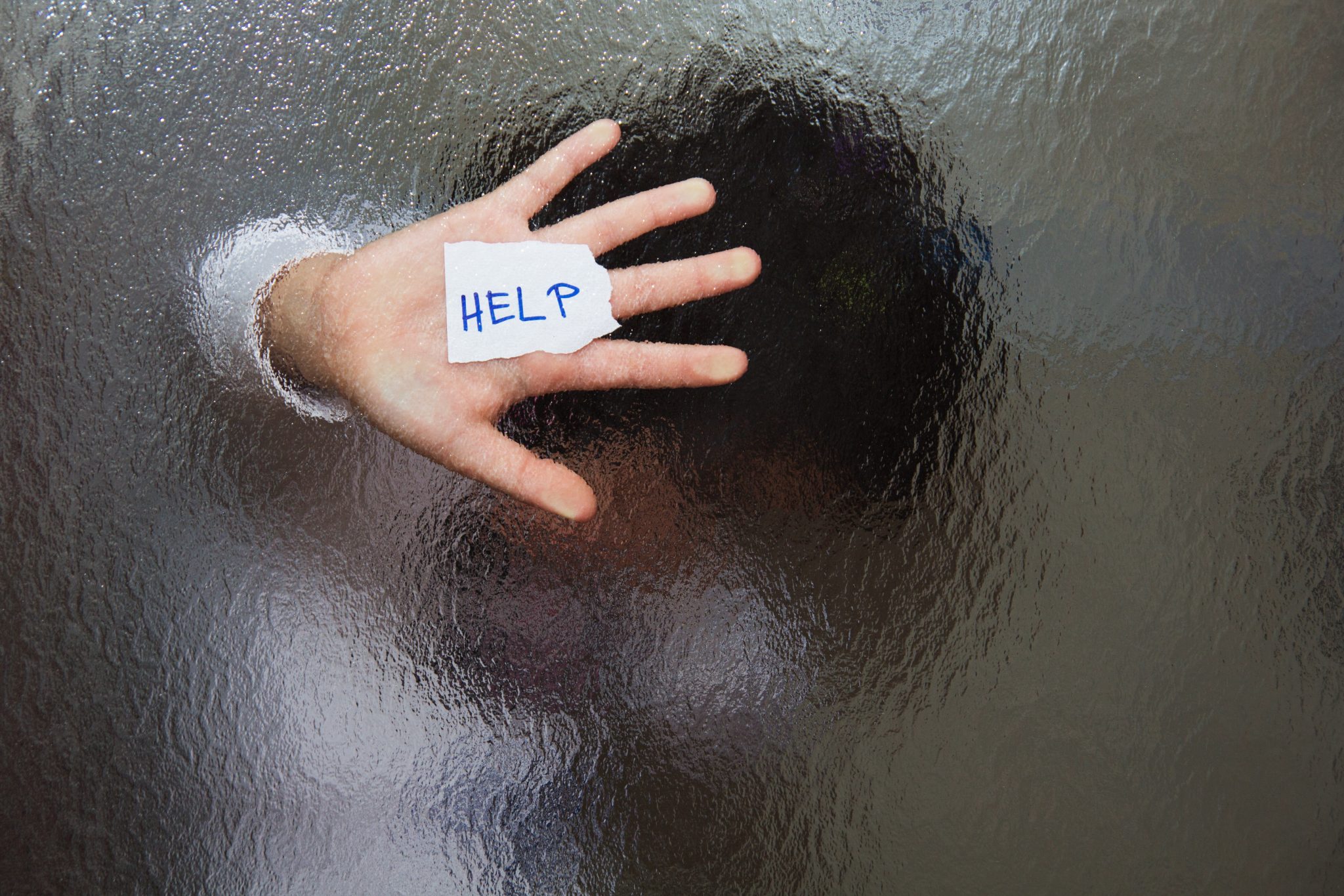 Woman behind glass door with 'Help' message