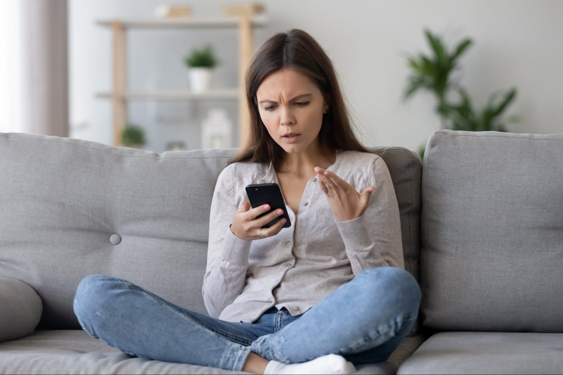 Young woman looking frustratedly at her mobile phone