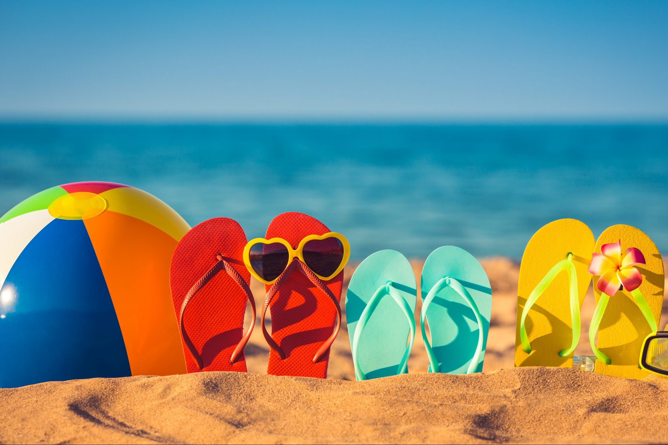 Beach ball and flip flops on a beach