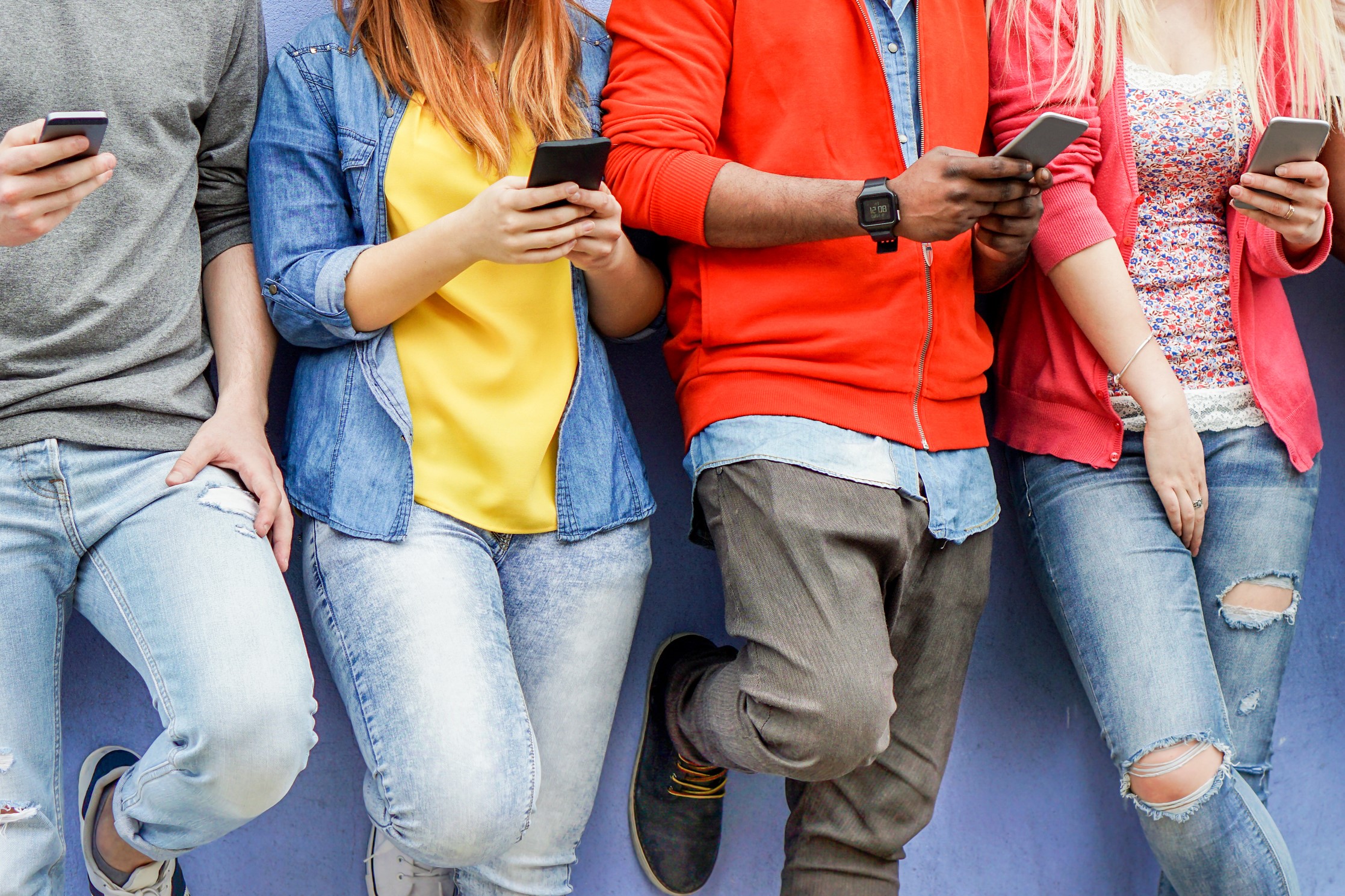 Young people in colourful clothes on their smartphones