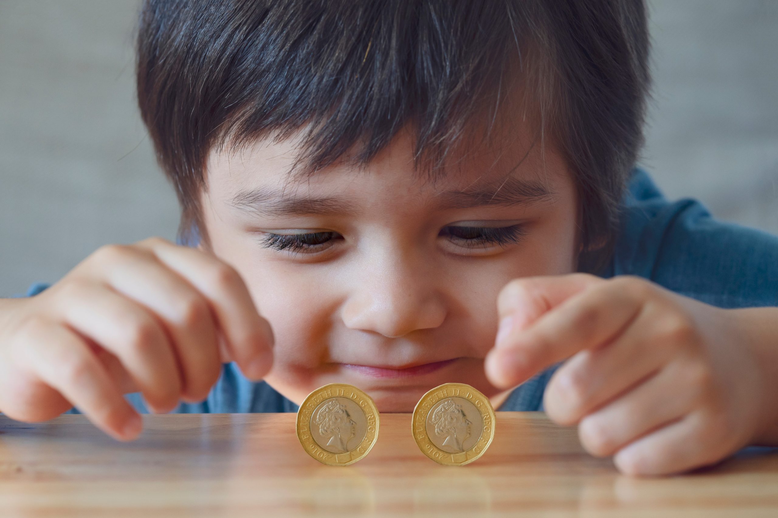 Boy playing with two pound coins