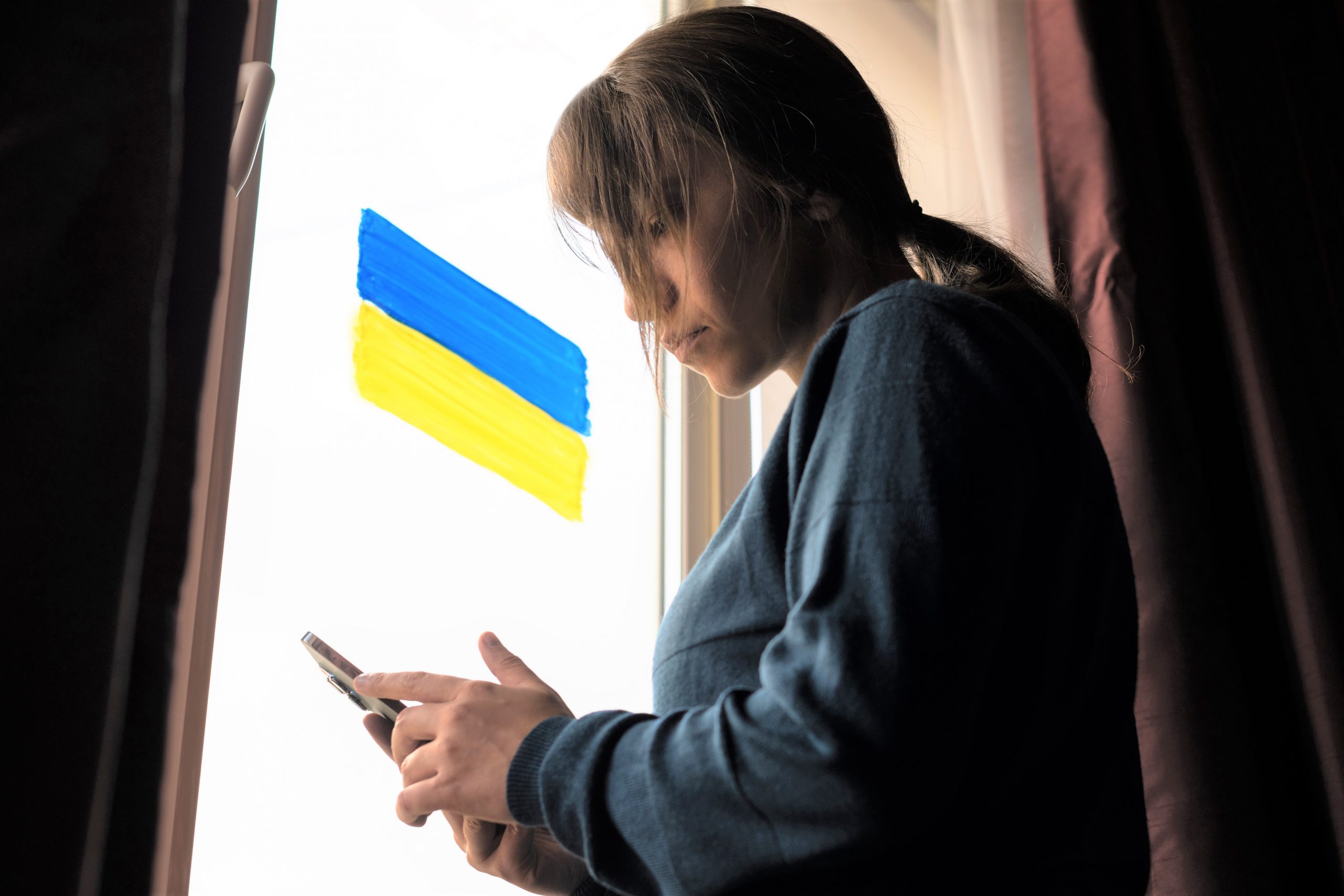 Young woman looking at news about Ukraine on smartphone