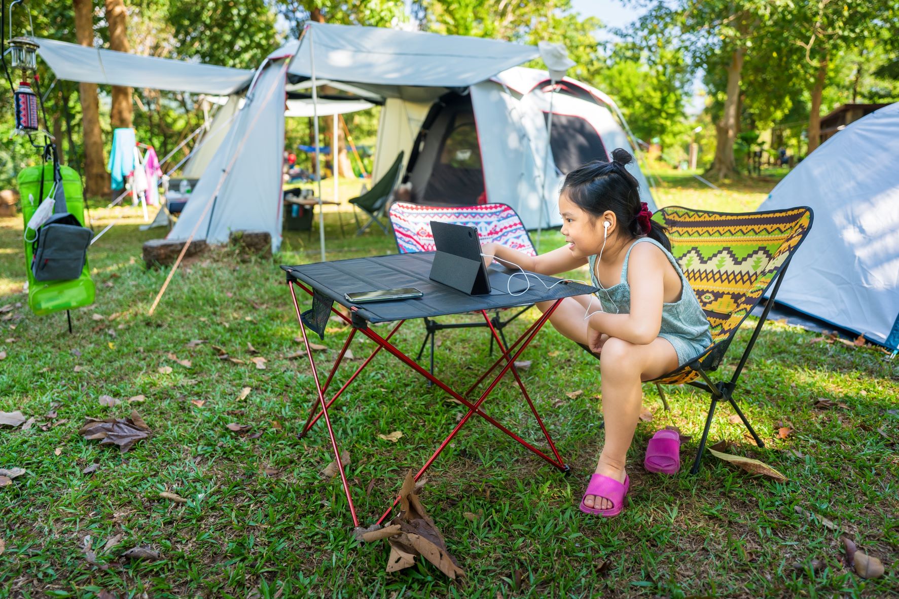 Young girl on tablet computer next to tent