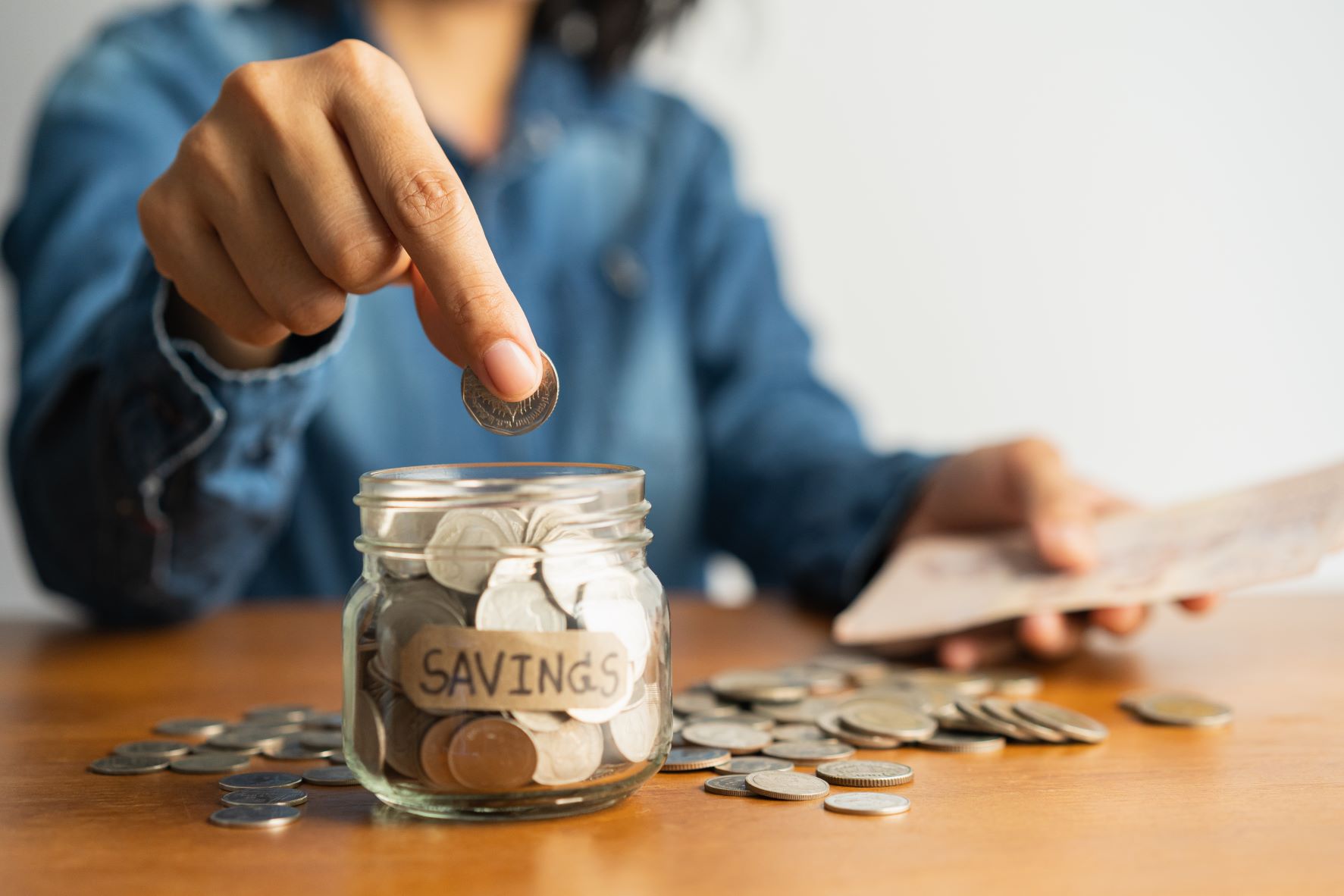 Woman putting coins in a savings jar