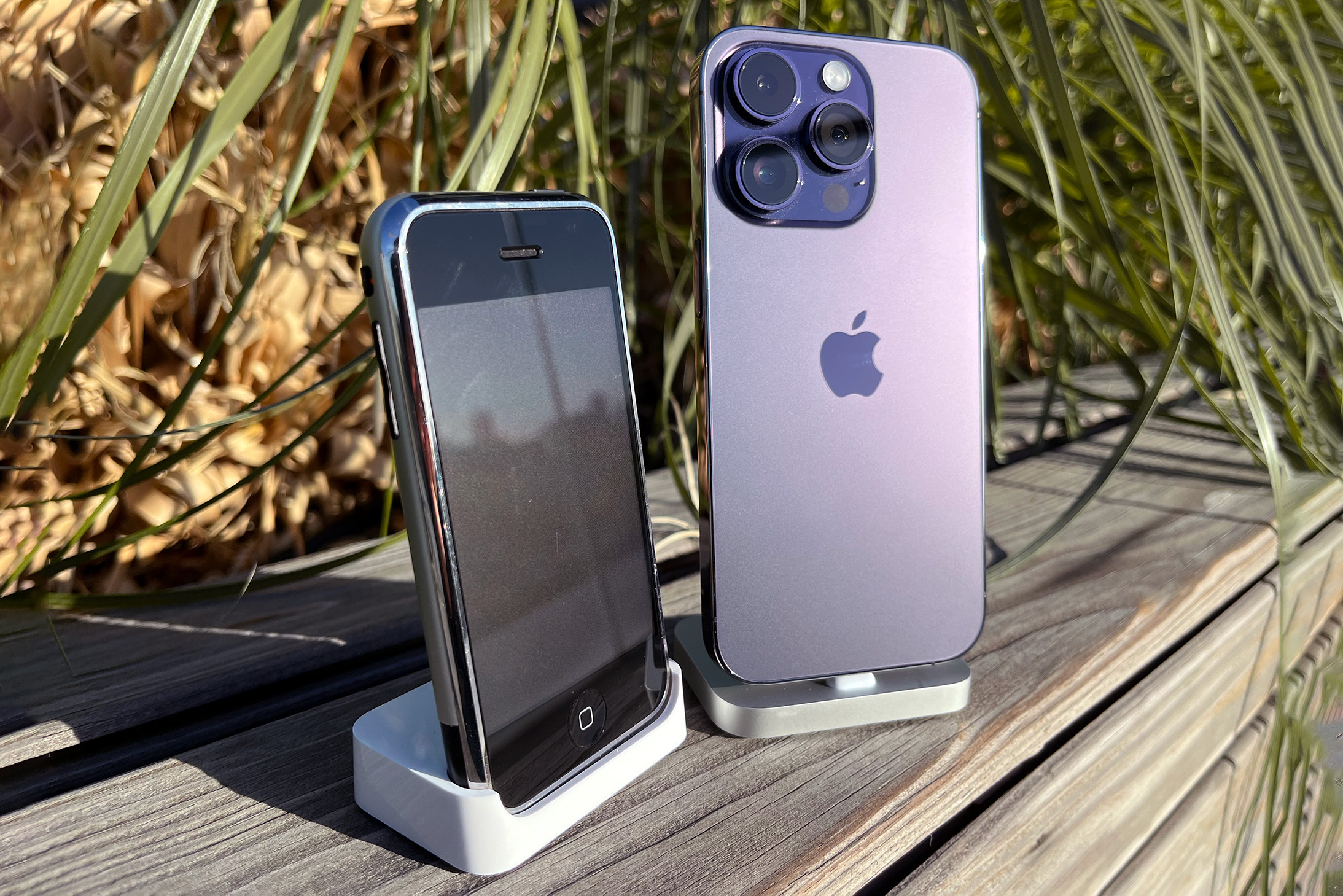 an original iPhone seen from the front alongside an iPhone 14 Pro as seen from the rear