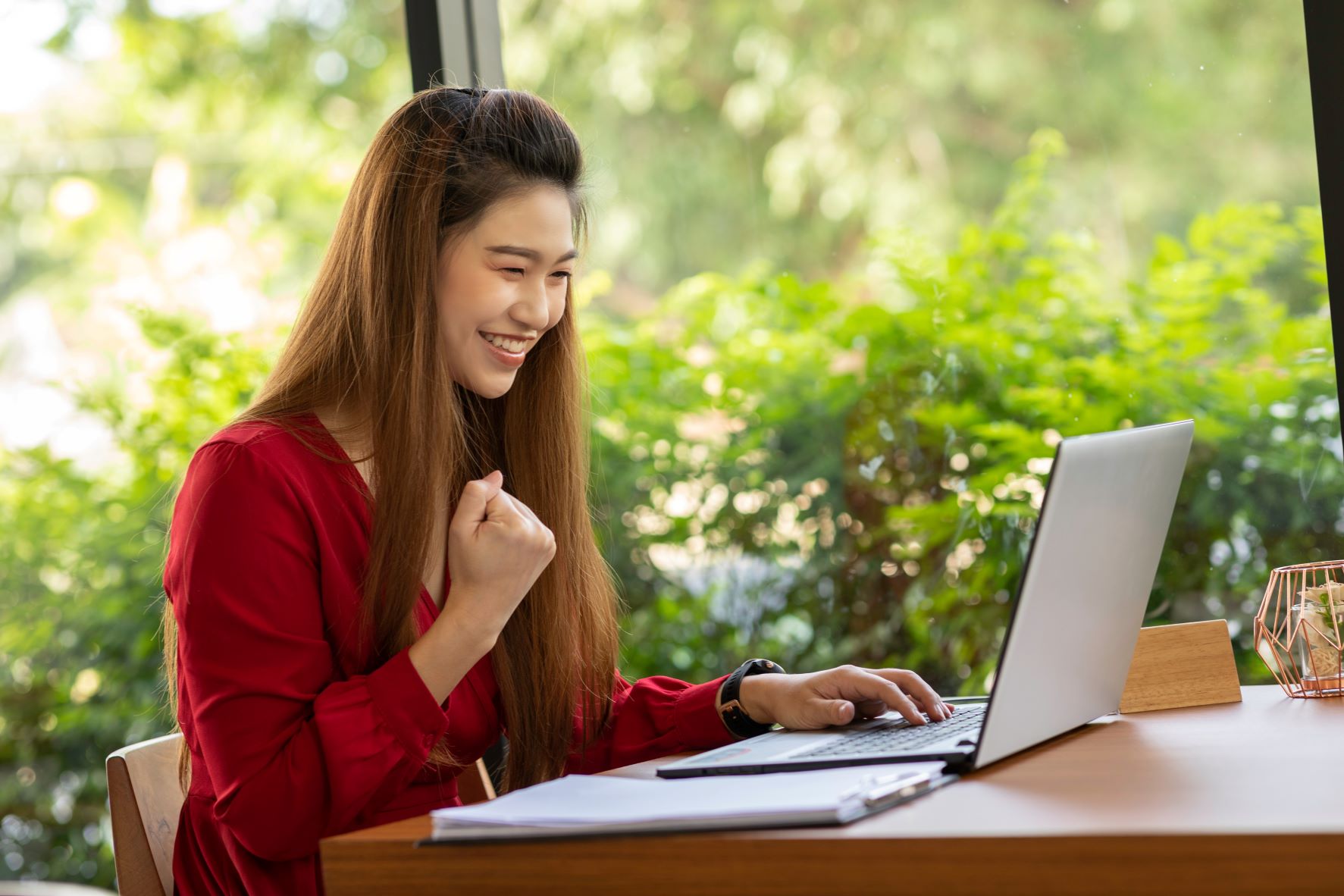 Young woman smiling and pumping fist at laptop