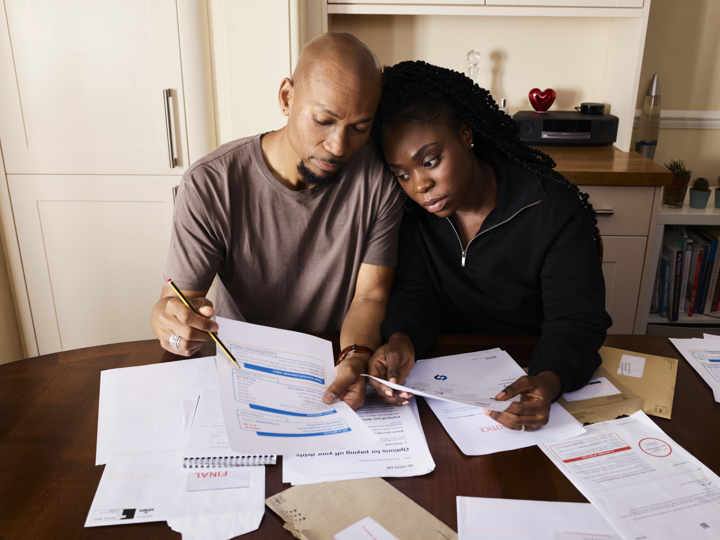 photo of a couple at a kitchen table examining bills
