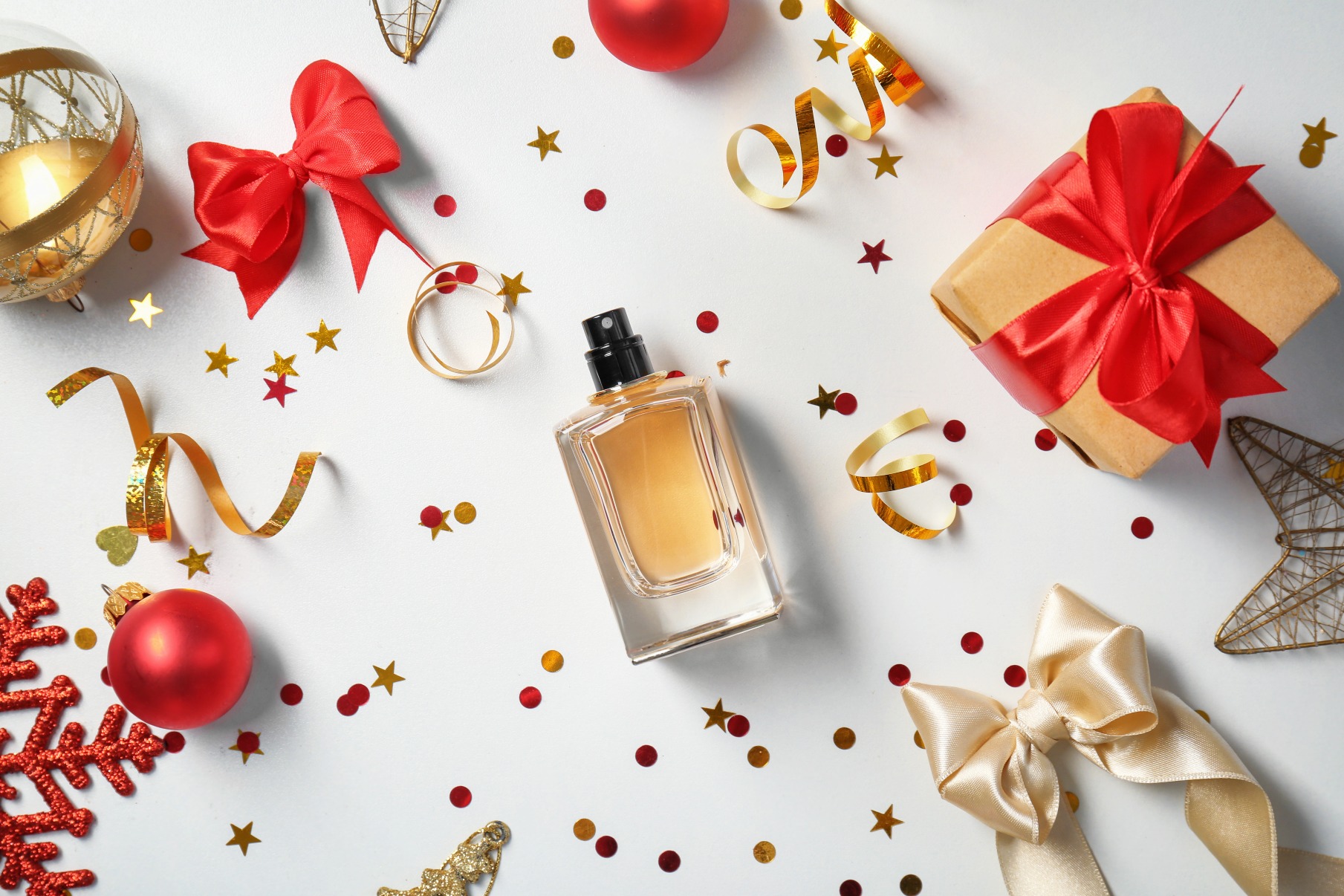 photo of a perfume bottle on a blank white surface surrounded by gift wrap