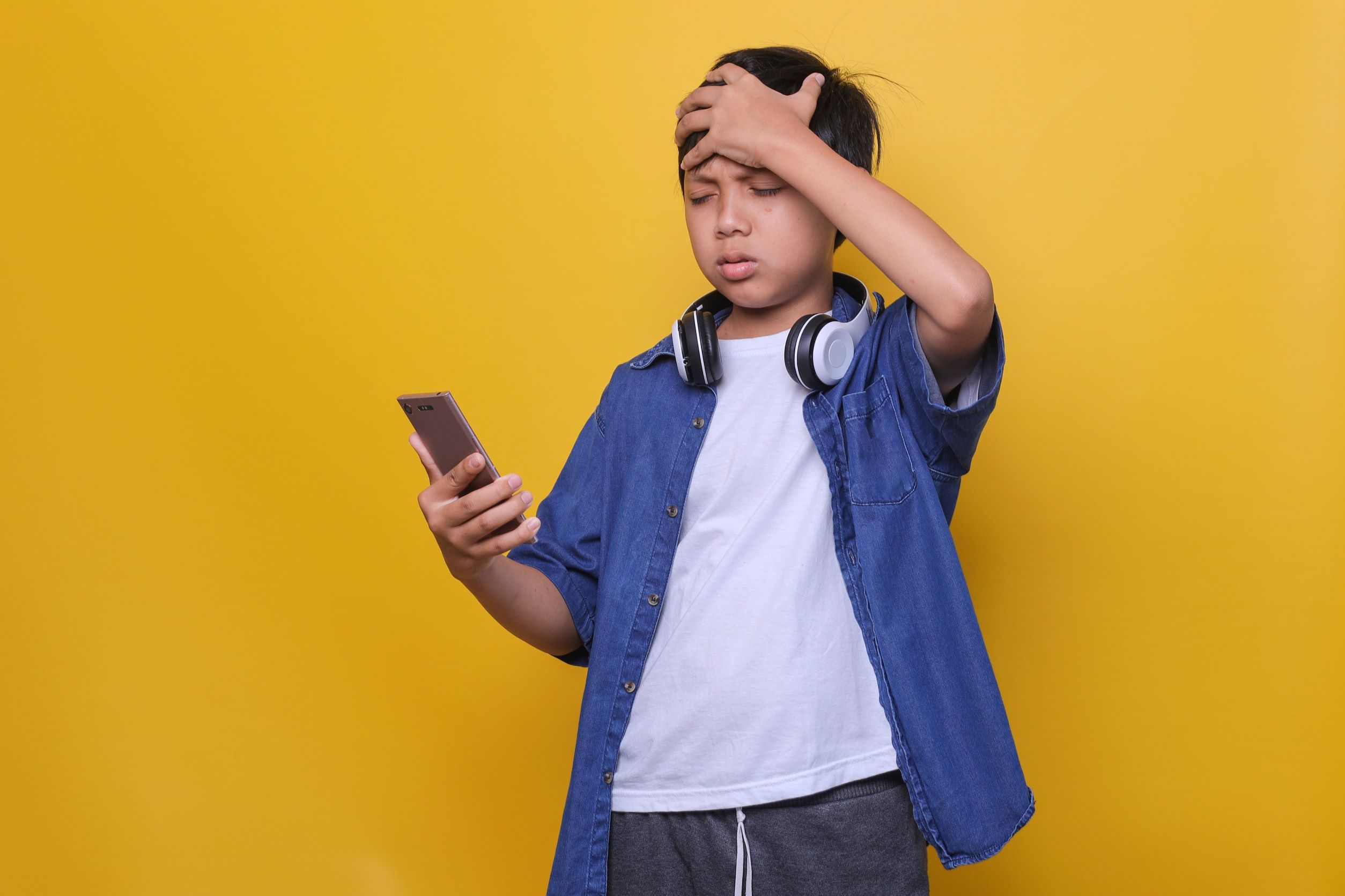 Upset young boy looking at smartphone