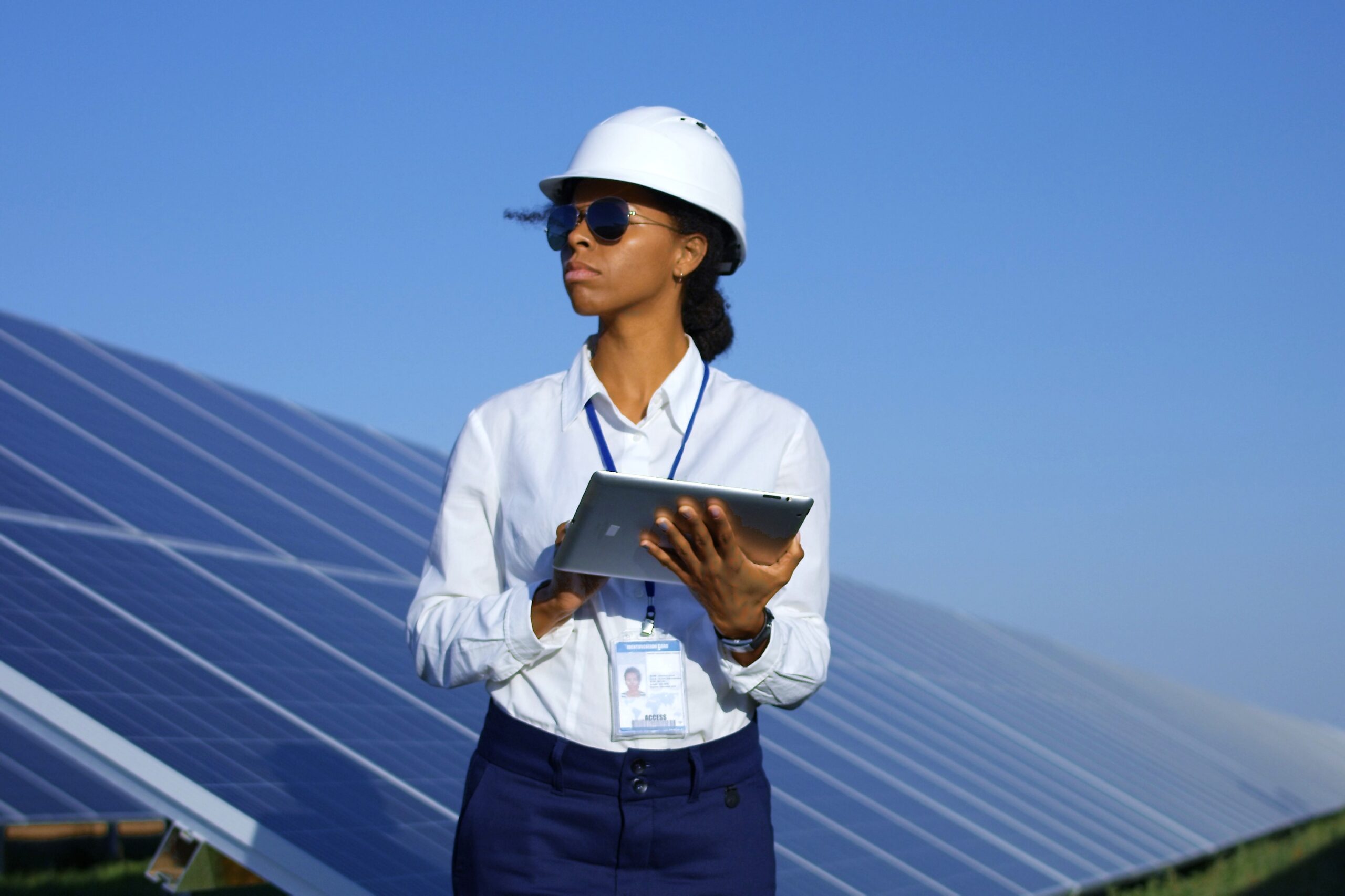 stock photo of a female engineer standing with a tablet in front of solar panels