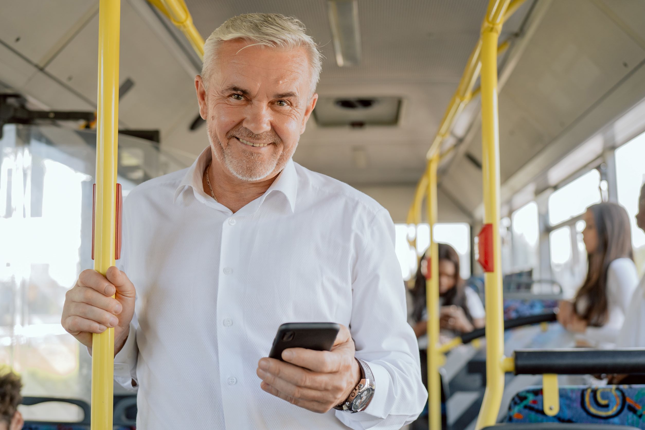 Smiling Middle Aged Man Holding Smartphone On Bus