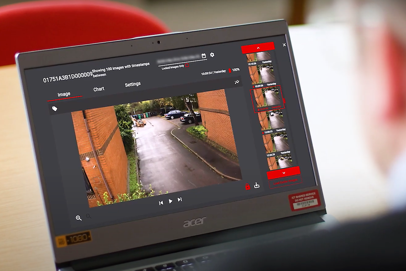 photo looking over the shoulder of a man looking at a laptop showing footage of flytipping from a Vodafone Smart Camera