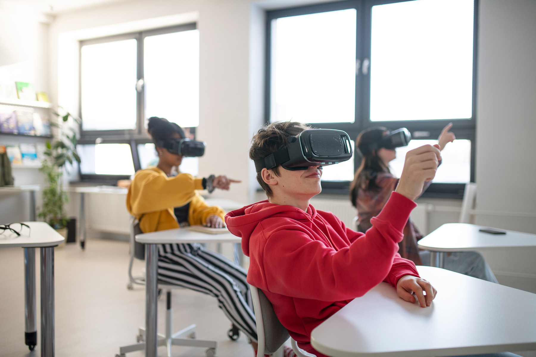 Teenage students wearing virtual reality goggles at school.