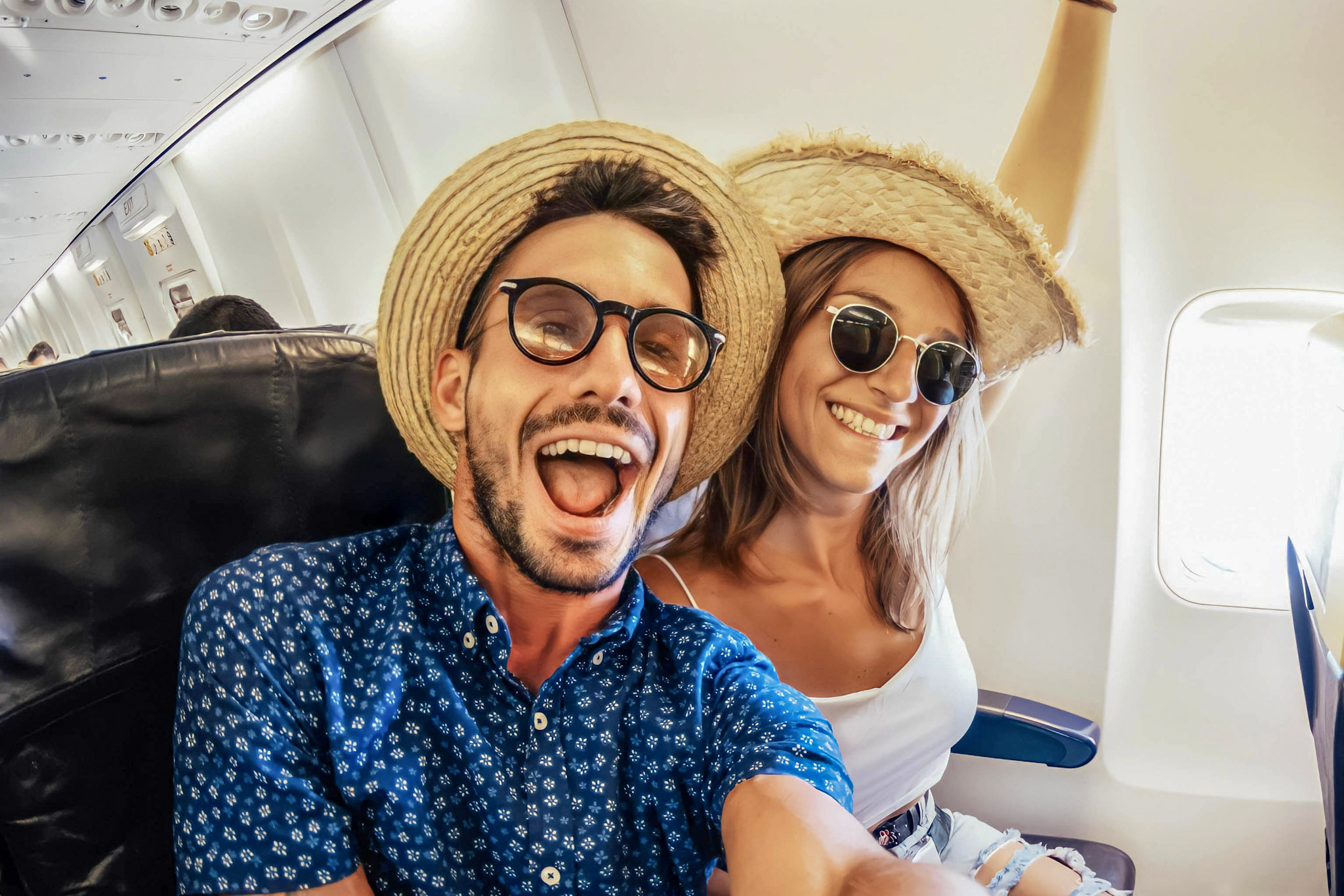 stock photo of a tourist couple taking a selfie in an airplane cabin