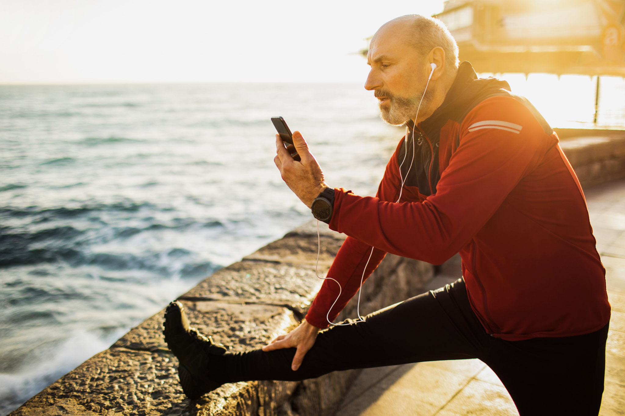 stock image of a man stretching outside while also using a smartphone