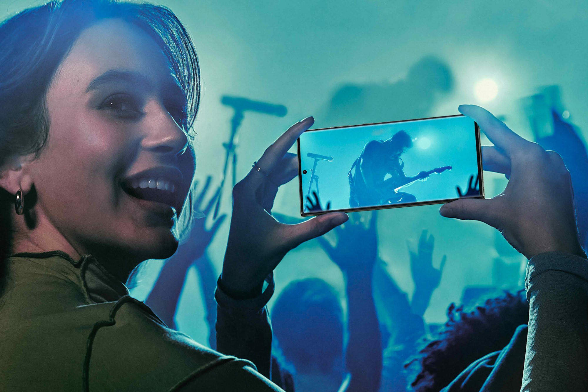 promotional image of a young woman using a Samsung Galaxy S23 smartphone at a concert