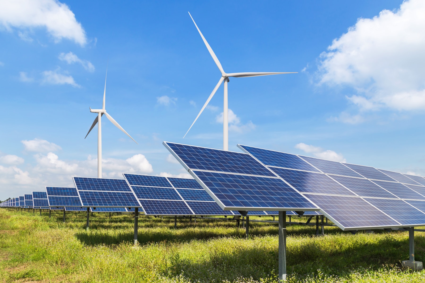 Renewable energy concept: Solar panels with wind turbines in the background