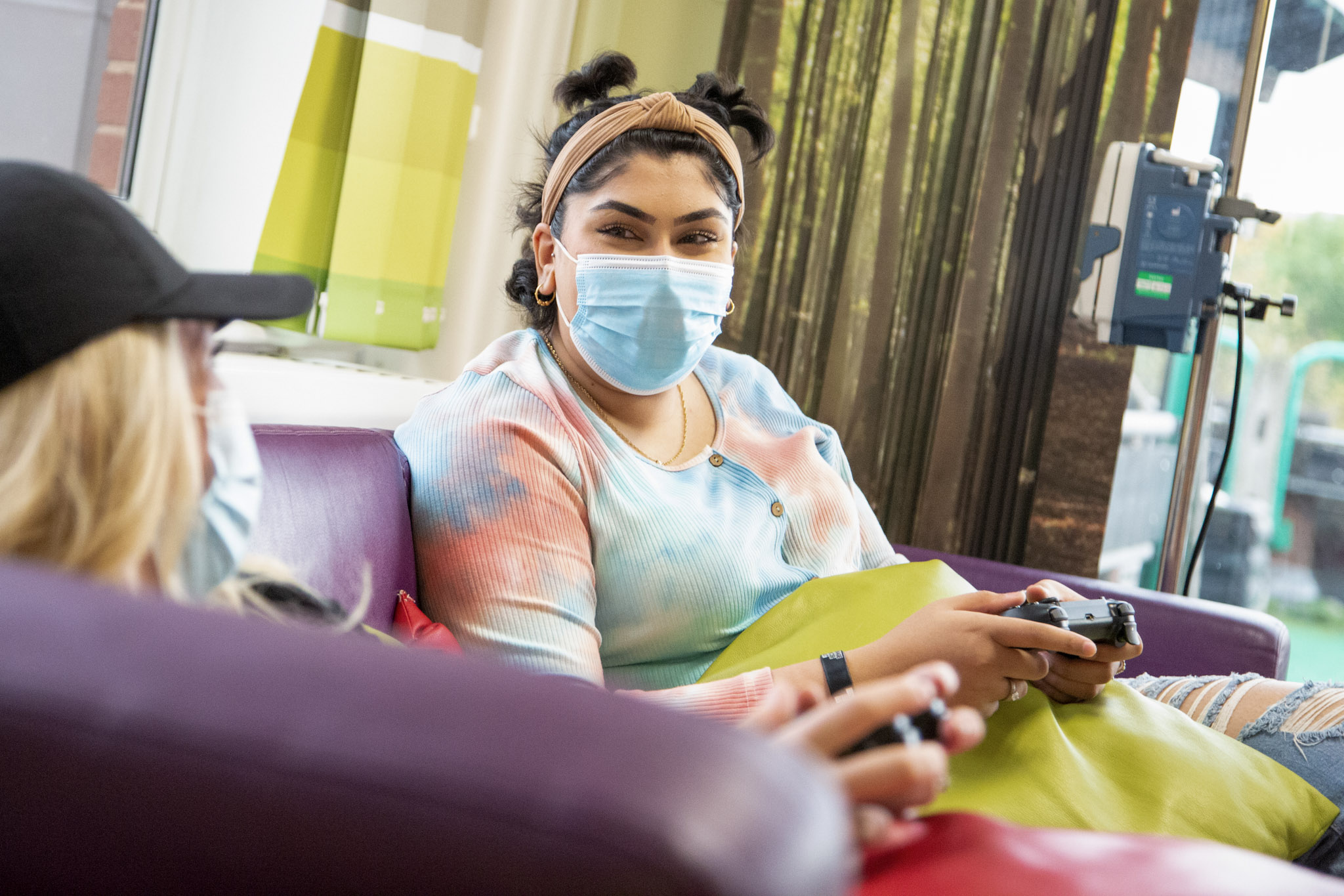 image of a teenage cancer patient playing video games while wearing a face mask