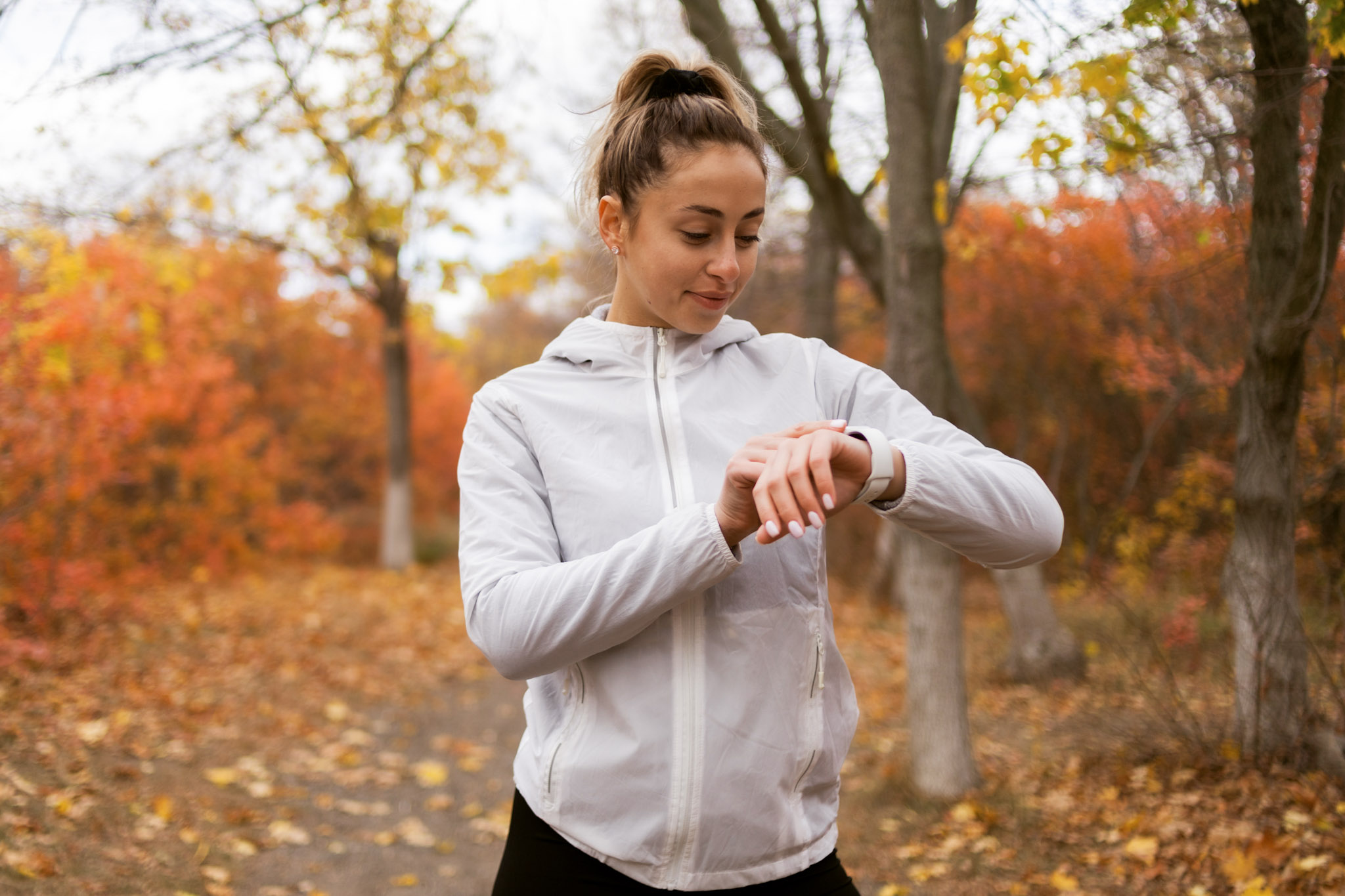 stock photo of a woman using a smart watch in an autumnal forest