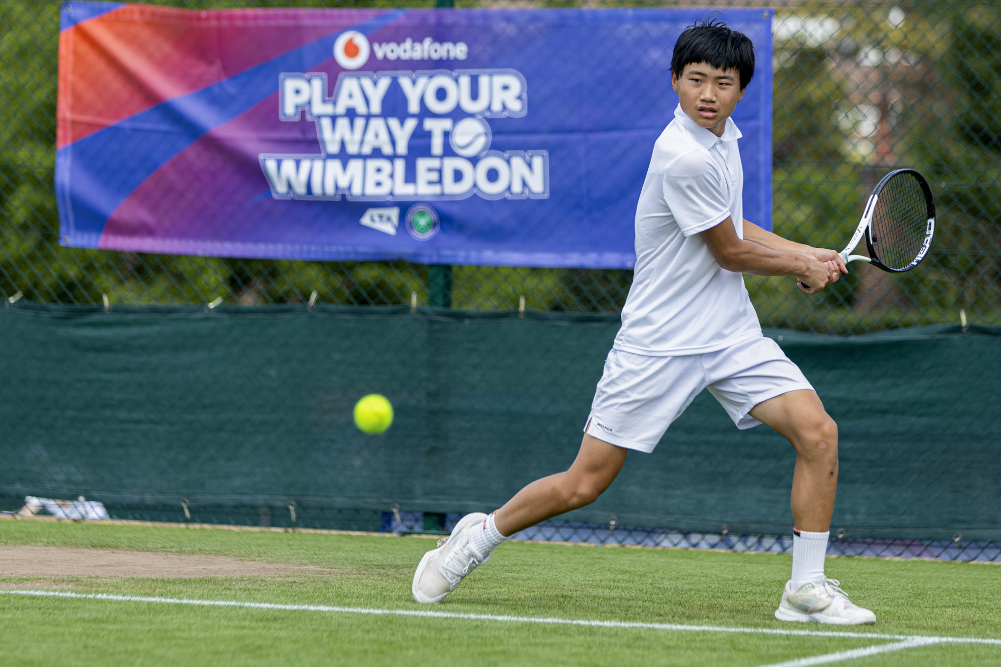 image of a boy playing tennis on a grass court