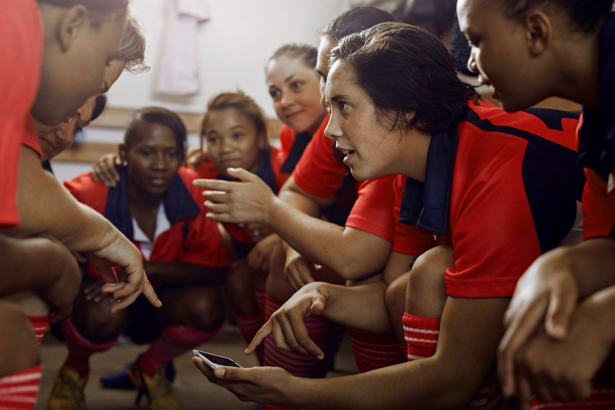 stock image of women's team players huddling around a smartphone