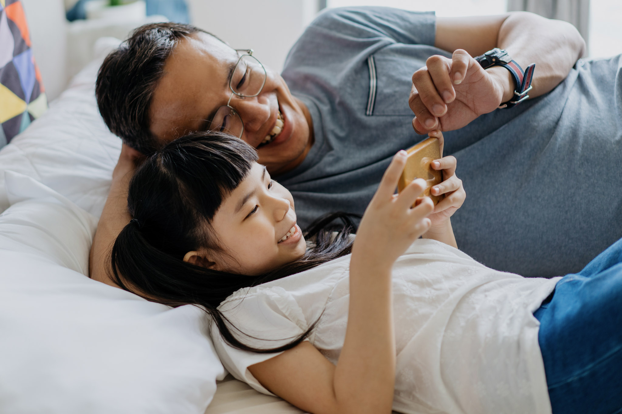 stock image of a young girl and her father using a smartphone