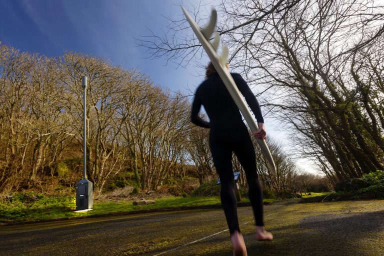A surfer going past the UK's first successfully tested 4G mini mobile mast, installed at Porthcurno, Cornwall