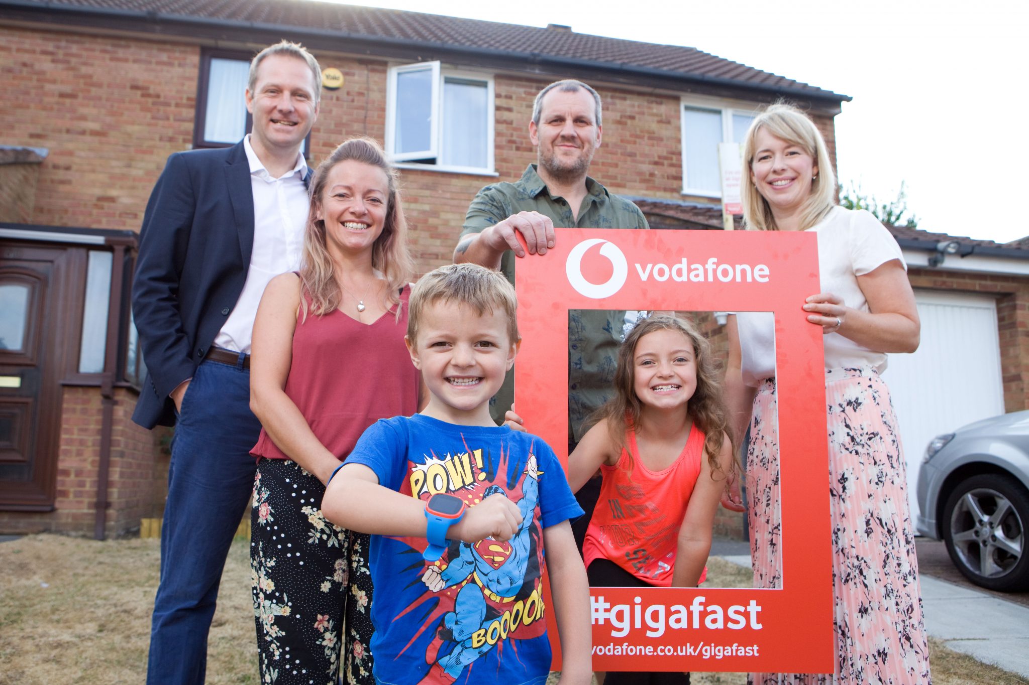 Photo of Vodafone UK’s Neil Blagden, Director of Digital & Commercial Operations (far left) and Kate Wright, Head of Consumer and Innovation, (far right) with the first Vodafone Gigafast Broadband family in Milton Keynes. Parents Micaela and Chris are now receiving broadband speeds of up to 1,000 Mbps with Vodafone. Their two children Daisy and Harry are wearing Vodafone’s new V-Kids Watch.