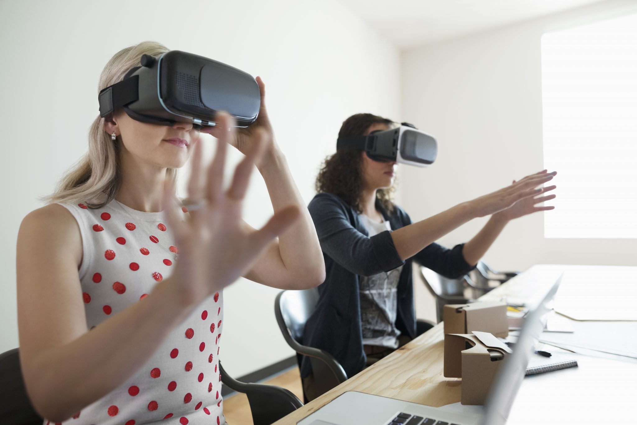 Photo of two women using VR headsets in the office