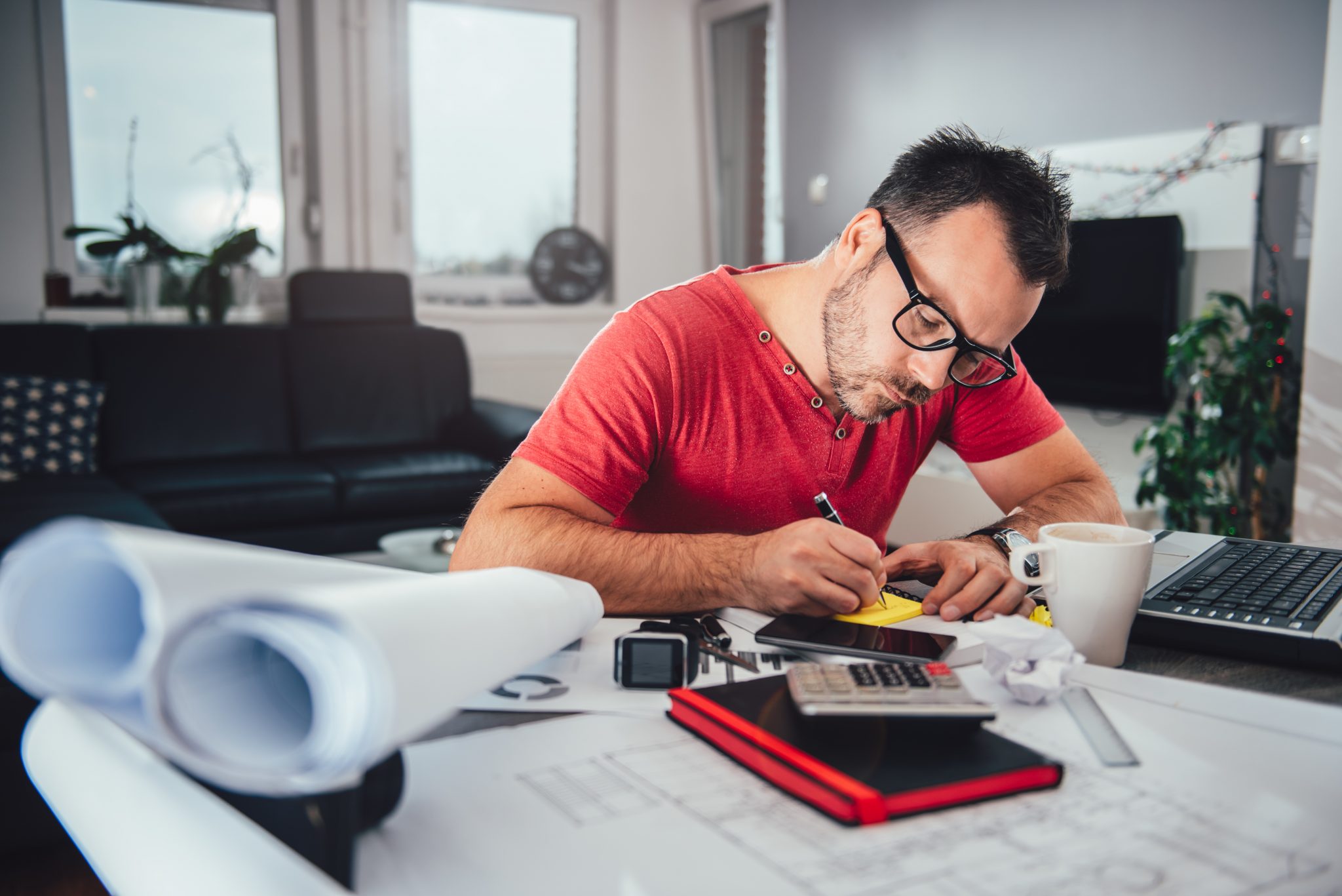 Man writing notes on memo pad Man working at desk from home