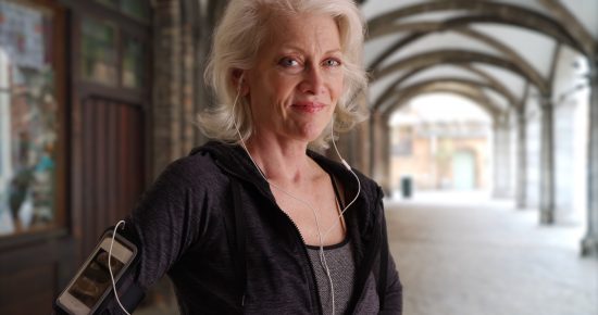 Older woman out exercising with smartphone and earphones