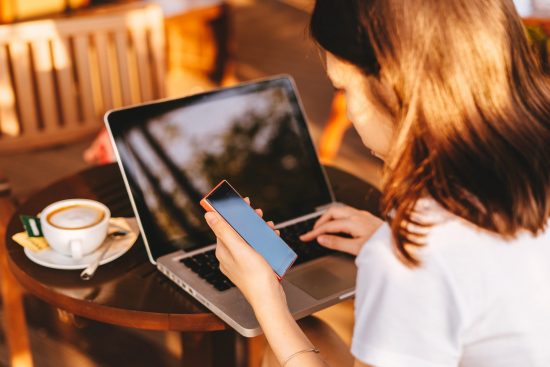 Woman working at table on laptop and phone