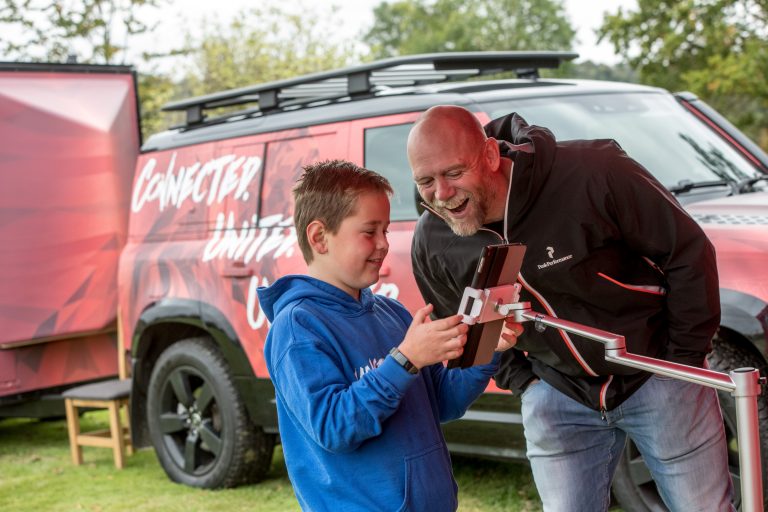 illustrative photo of Mike Tindall and a local boy playing a game on a tablet