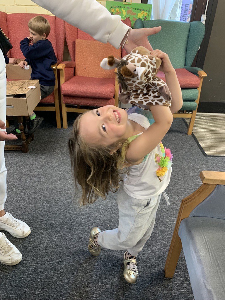 Ukrainian refugee girl playing with toy giraffe puppet