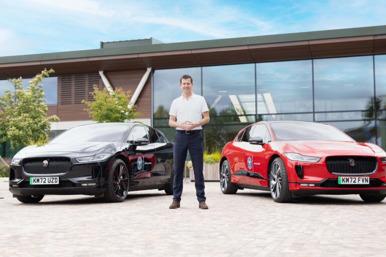 Tim Henman standing next to Jaguar's from Wimbledon's fleet.