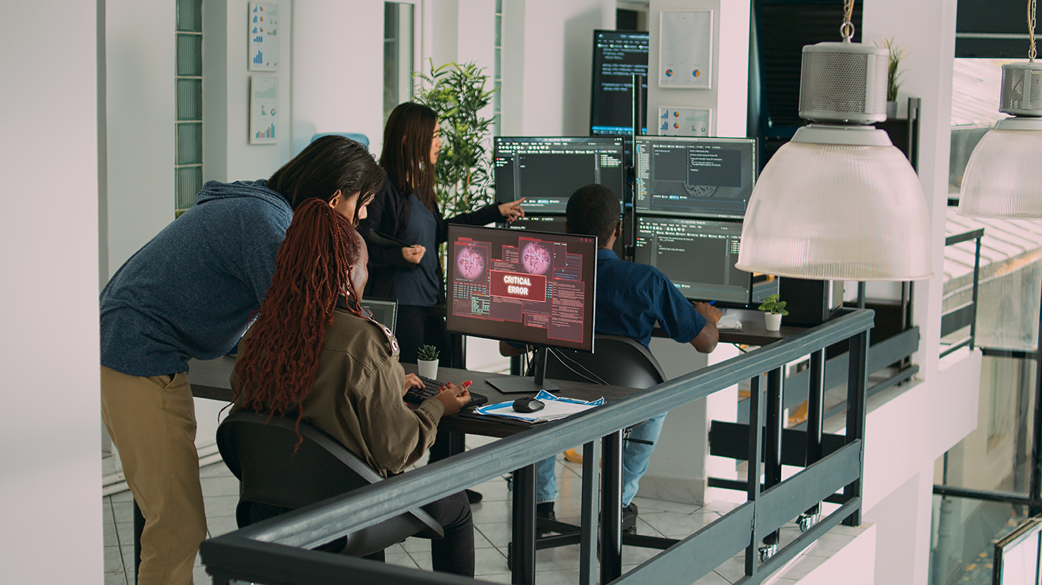 Office workers dealing with cybersecurity issues on computers.