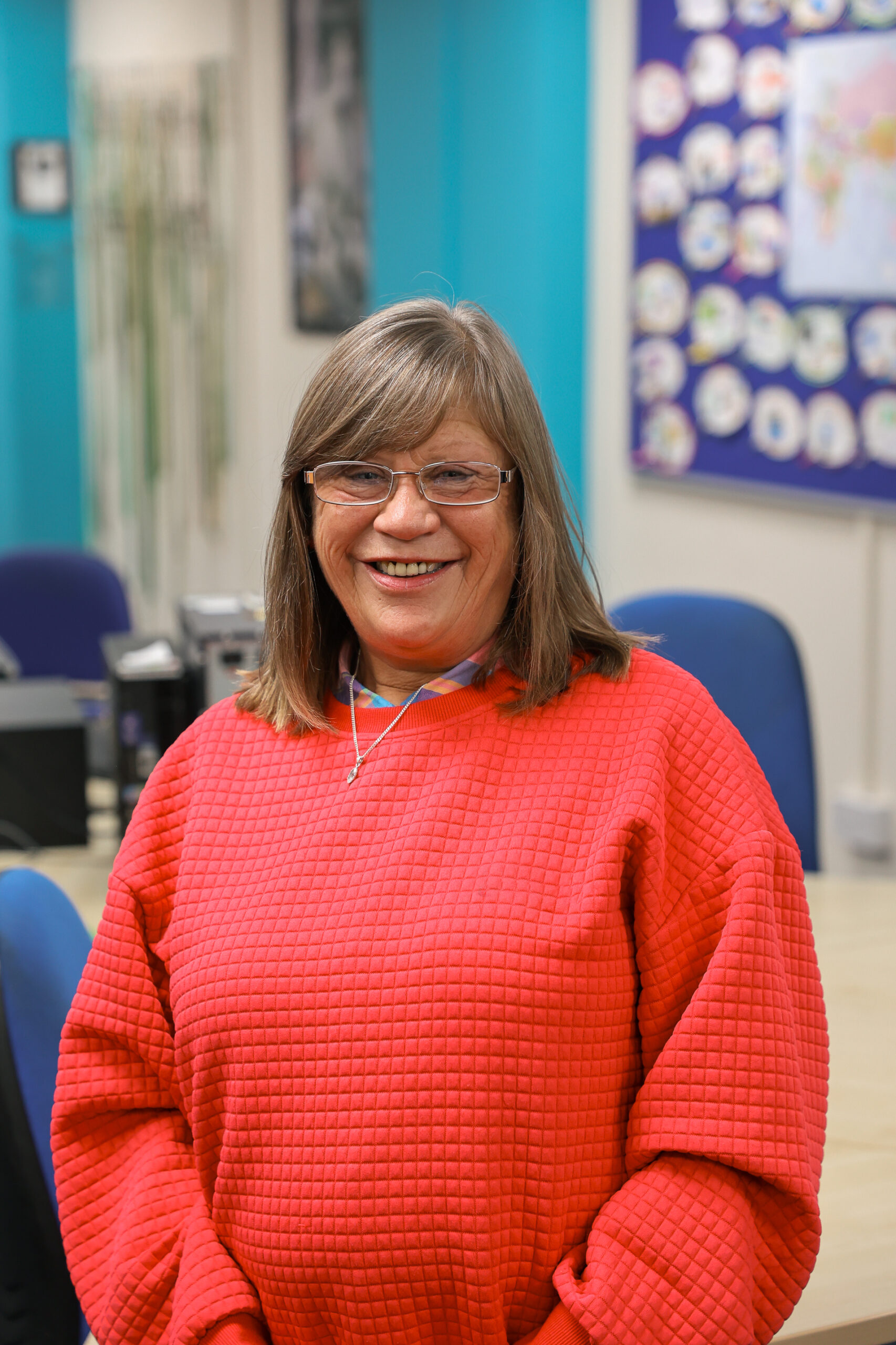 Woman in red jumper, smiling at camera.