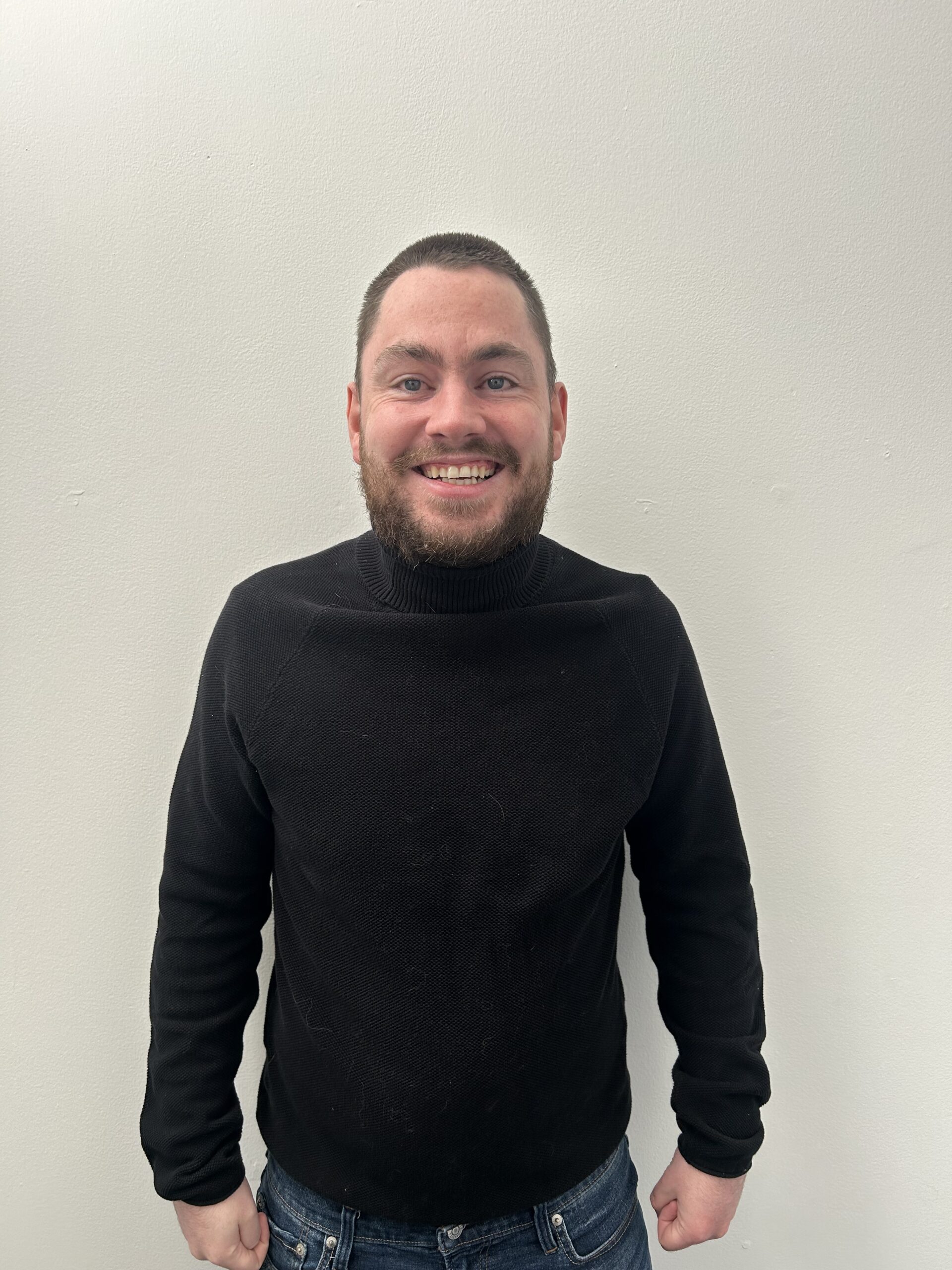 Man in black, smiling at camera.