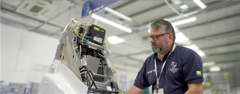 Male Optos worker in factory with machinery.