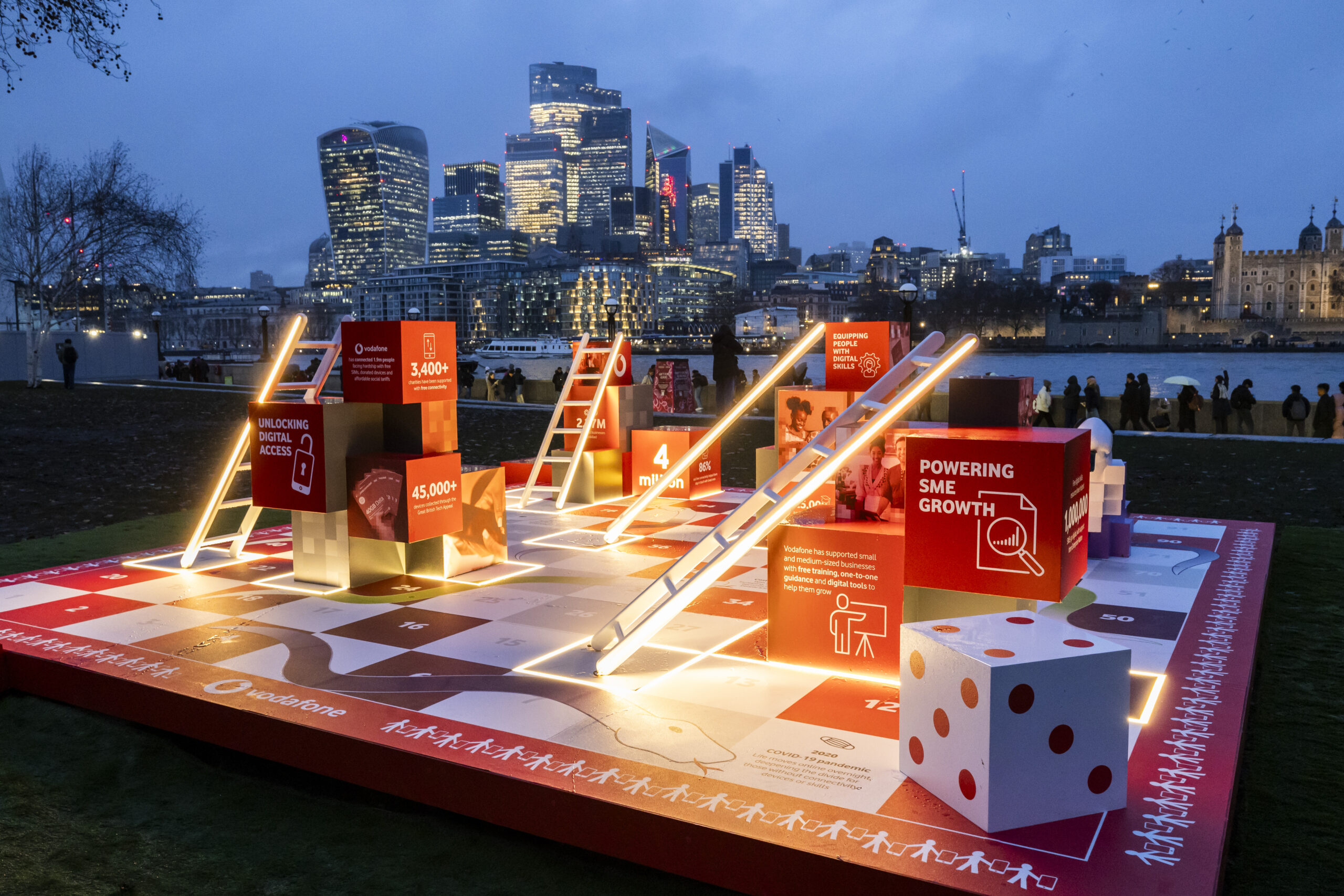 Vodafone's Snakes & Ladders installation for everyone.connected, with London skyline in background, at night.