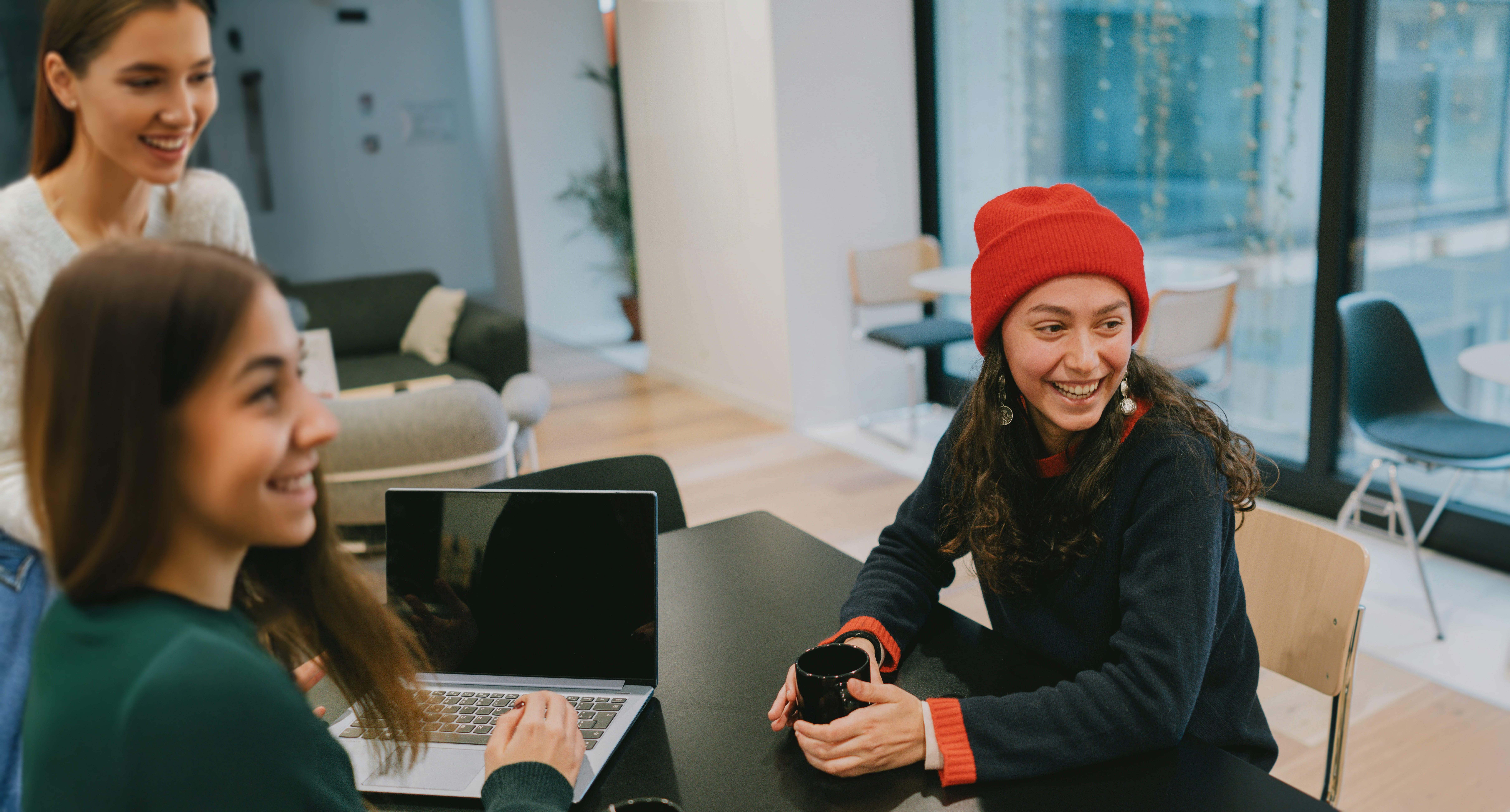 Three young women sat at table, smiling.