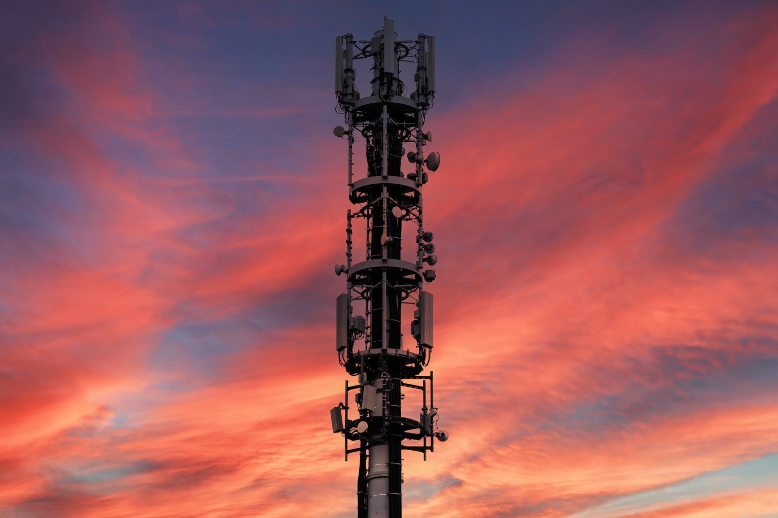 Mobile phone mast set against dramatic sunset skyline.