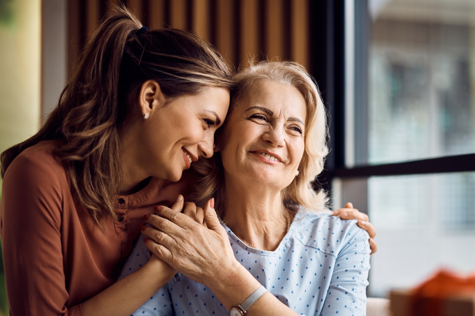 Adult women showing affection to older mum.