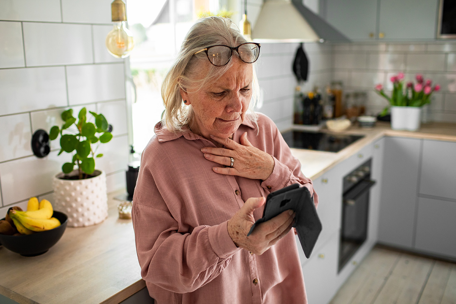 Concerned senior woman reading smartphone in home kitchen_1878055529 Adobe Stock