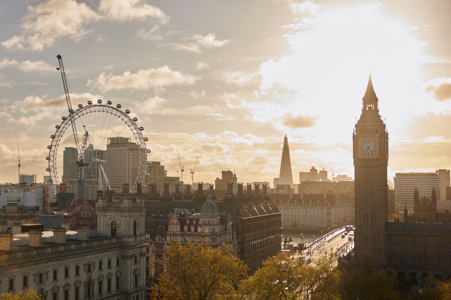 London skyline, featuring London Eye and Big Ben, at sunset.